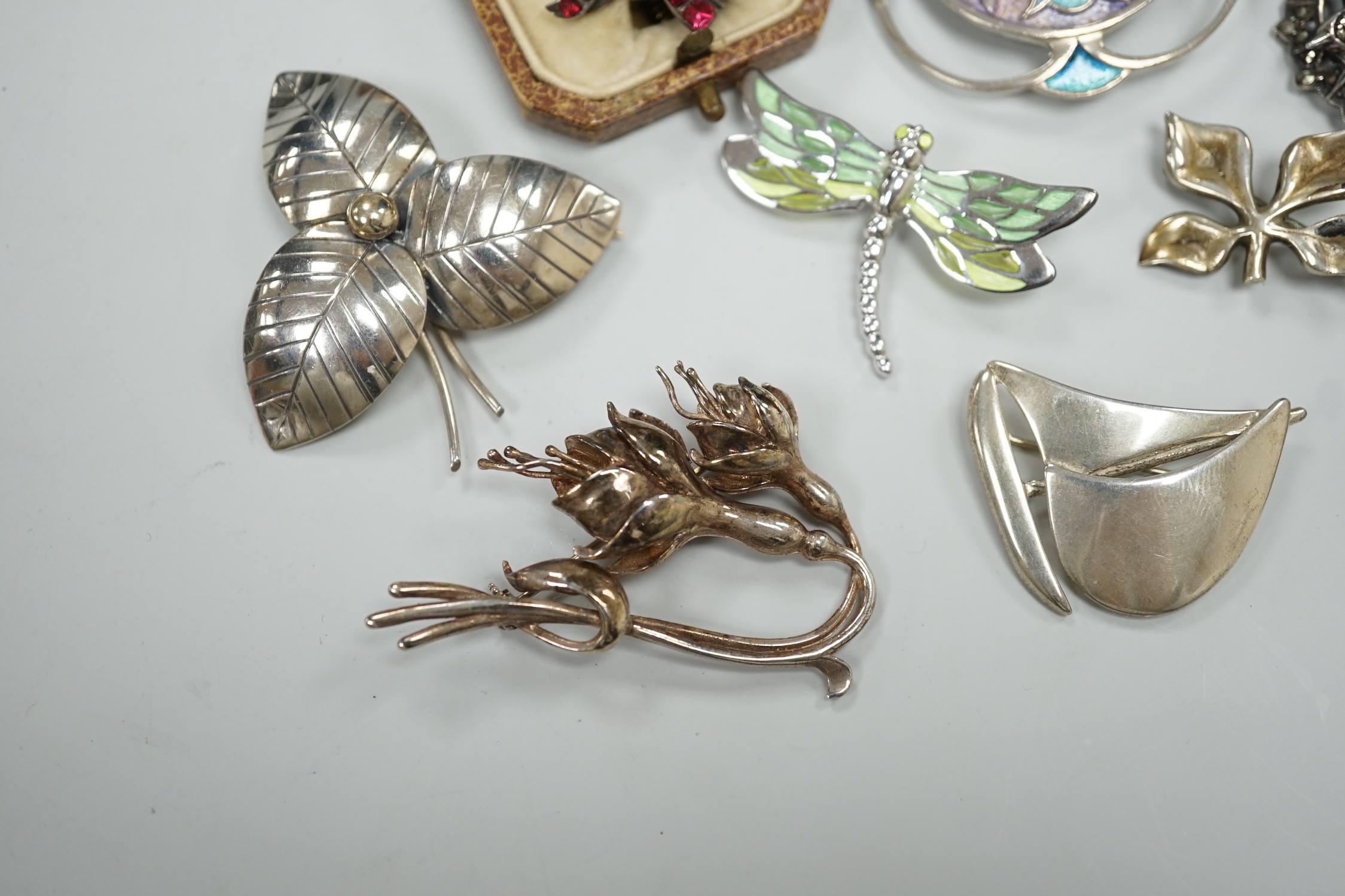 An early 20th century white metal and foil backed garnet cluster set bird brooch, 27mm and eight other assorted mainly 925 brooches including two enamelled and one Finnish yacht brooch.